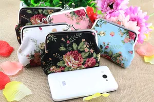 Detail of vintage canvas floral coin purses with metal kiss-lock and phone size reference