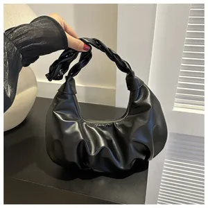 Detail of black pleated croissant bag with woven handle and gold zipper closure