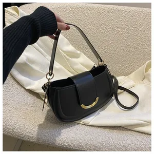 Close-up of black leather saddle bag with golden crescent buckle and adjustable strap