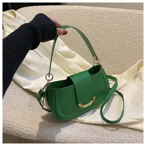 Detail of green PU leather saddle bag with gold metal clasp and adjustable shoulder strap