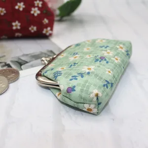 Detail view of green floral cotton fabric and vintage silver metal kiss lock clasp