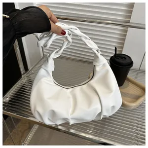 Close-up of white ruched shoulder bag with a twisted handle and soft leather texture