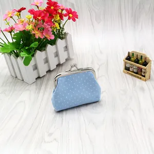 Close-up of light blue polka dot fabric coin purse with silver metal clasp on wood