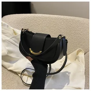Detail of minimalist black crescent bag with elegant gold half-moon metal buckle closure