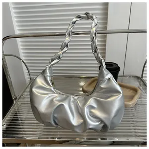 Detail of silver metallic hobo bag featuring a twisted handle and pleated PU leather