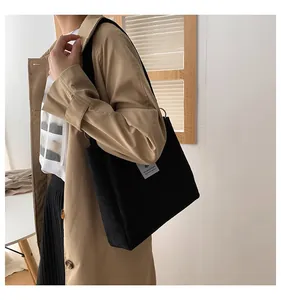 Detail of black corduroy tote bag showing textured fabric and stylish casual outfit