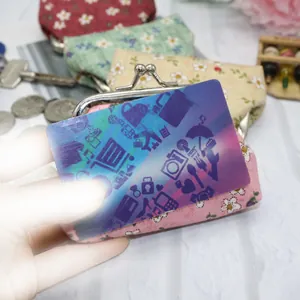 Floral print fabric mini coin purse with metal clasp closure on a rustic wooden background