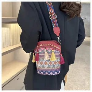 Dettaglio borsa a secchiello boho con trama geometrica e nappe colorate a tracolla