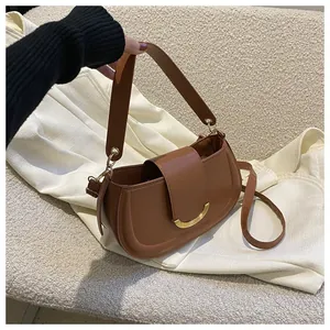 Detail of caramel saddle bag with golden metal buckle and versatile shoulder straps