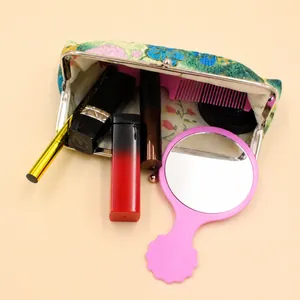 Détail d'une pochette à maquillage rétro en tissu fleuri avec fermoir en métal et contenu