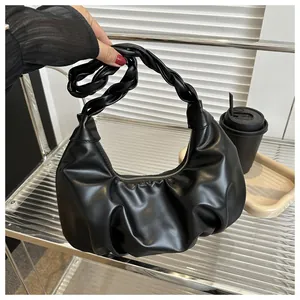 Detail of black pleated shoulder bag featuring a knotted handle and sleek zipper closure