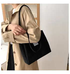 Black corduroy tote bag detail showing shoulder strap and vertical ribbed texture on model