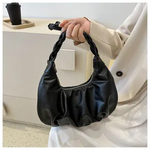 Close-up of black pleated dumpling bag with a unique woven handle and zipper detail
