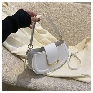 Detail of white saddle bag with golden U-shaped buckle on beige textured sofa