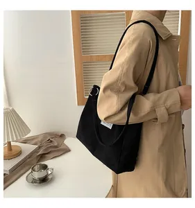 Detail of black corduroy tote bag with woven label and shoulder strap on a model