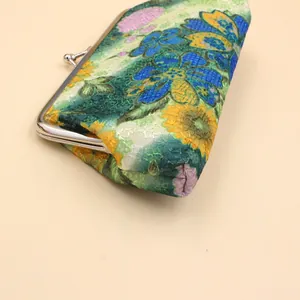 Détail de la broderie florale et du fermoir kiss-lock sur le long portefeuille en tissu