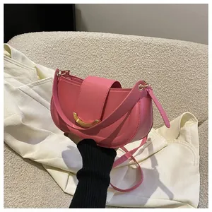Detailed view of pink saddle bag with golden crescent metal buckle on a white sofa