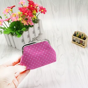 Pink polka dot canvas coin purse with silver metal kiss-lock frame held by hand