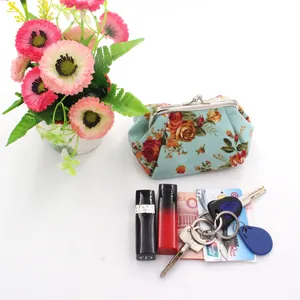 Detailed view of floral canvas coin purse holding lipstick, keys and bank cards
