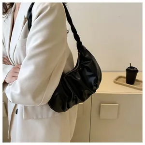 Detail of black crescent hobo bag with pleated texture and braided strap on a model