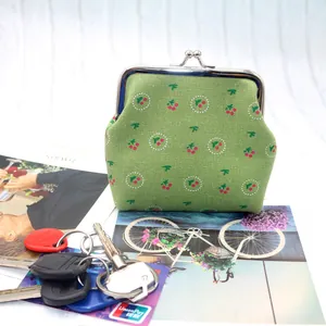 Porte-monnaie en coton vert à motif cerise avec fermoir métallique sur fond bois