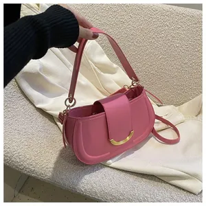Close-up of pink saddle bag featuring a textured finish and golden crescent metal buckle