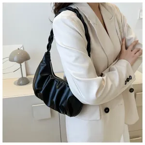 Detail of black pleated PU leather handbag with distinctive braided shoulder strap