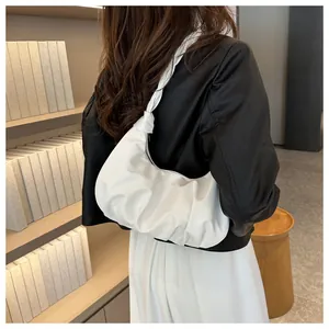 Detail of white pleated dumpling bag showing leather texture and knotted shoulder strap