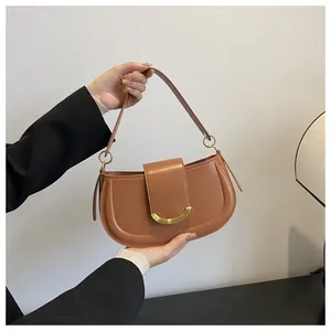 Detailed side view of a brown leather saddle bag with golden crescent metal buckle closure