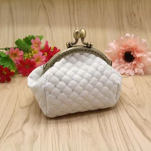 Vintage white quilted coin purse with sequins and embossed bronze metal clasp on wood