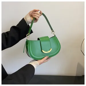 Detail of green saddle bag with gold crescent buckle and smooth matte synthetic leather