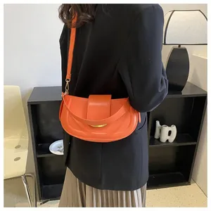 Detailed close-up of a bright orange saddle shoulder bag with smooth leather finish