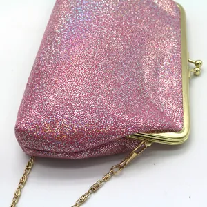 Detail van roze glitter avondtas met gouden kiss-lock sluiting en metalen ketting