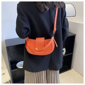 Detail of adjustable strap and metal buckle on orange saddle bag shown in a lifestyle scene