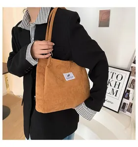 Detailed view of ginger corduroy tote bag featuring white woven label on model