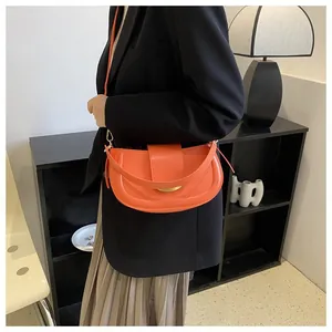 Orange matte leather saddle bag worn with a black blazer for a modern fashion look