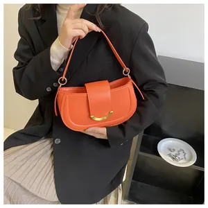 Detailed view of an orange leather saddle bag featuring a stylish golden metal clasp