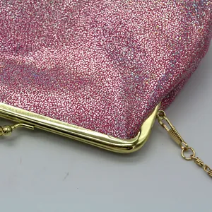 Detail van roze glitter clutch tas met gouden metalen frame en bolvormige sluiting