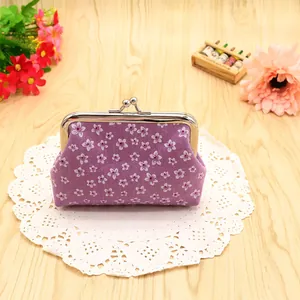 Close-up of purple floral coin purse with silver metal clasp on a wooden desk