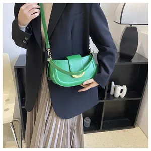 Close-up of a bright green saddle bag with gold metal buckle worn by a model