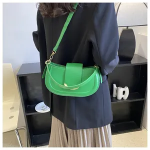 Detail of a bright green saddle bag with gold metal trim shown on a model