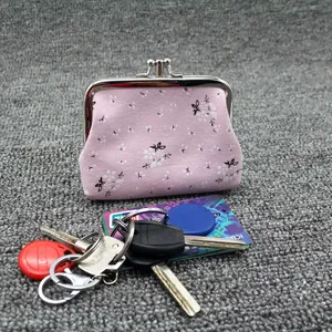 Close-up of pink floral fabric coin purse with metal clasp on a textured background