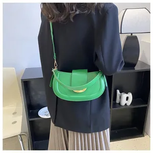 Detail of bright green crescent saddle bag with gold metal buckle on black blazer