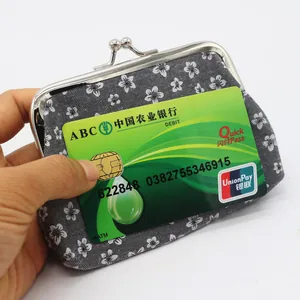 Close-up of small floral coin purse with vintage metal clasp next to a bank card