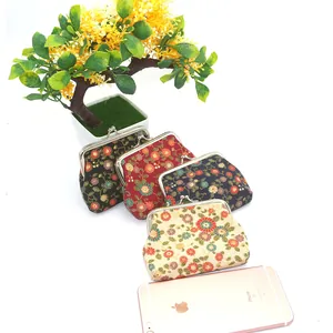 Detailoverzicht van vier vintage bloemenportemonnees met maatvergelijking met een telefoon