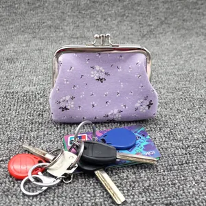 Detail of floral purple fabric coin purse with metal kiss lock, key and card for scale