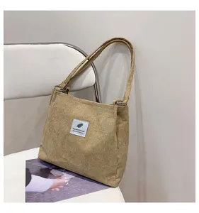 Close-up of light khaki corduroy tote bag texture with blue feather label on a white chair