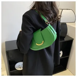 Detail view of a bright green saddle bag with gold horseshoe hardware on a black blazer