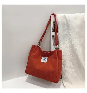 Detail of orange corduroy tote bag with silver metal ring connector and graphic patch