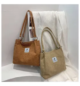 Detailed shot of corduroy tote bags with leaf pattern labels and metal ring hardware